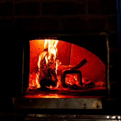 Interior of a wood-fired oven with a fire burning inside.