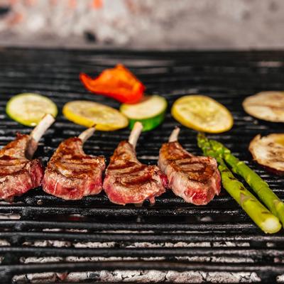 Lamb chops  and vegetables getting grilled.