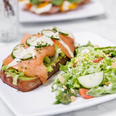 Smoked salmon avocado toast with cucumber and chives, served with a garden salad.