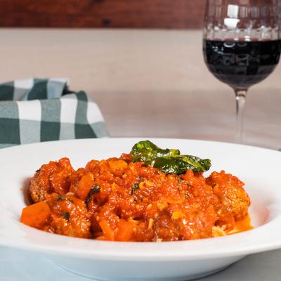 Spaghetti and meatballs served with red wine.