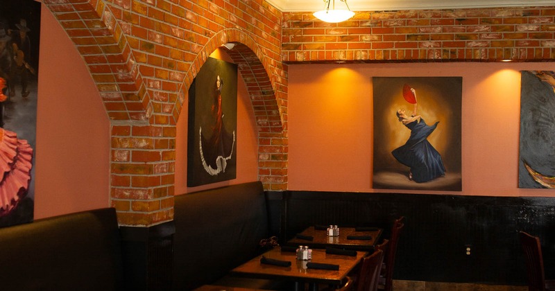 Interior, tables and chairs in dining area with paintings on the wall