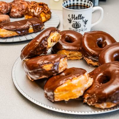 Plate of chocolate-glazed doughnuts served with a cup of coffee.