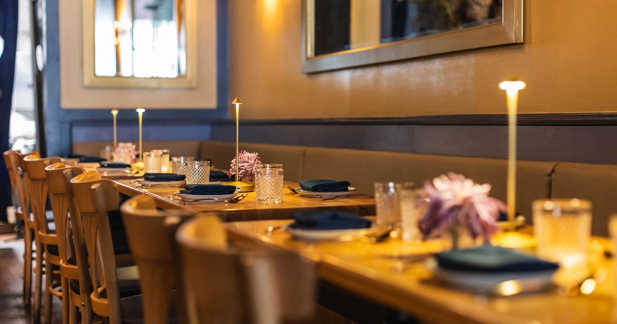 Wooden tables ready for service set along a banquette