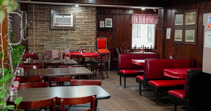 Interior of a wooden restaurant with tables and red booths.