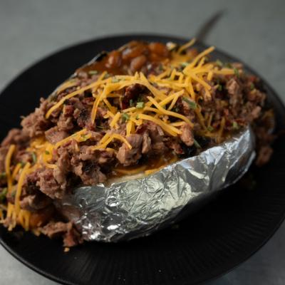 Loaded baked potato  topped with chopped barbeque meat and shreded cheese.
