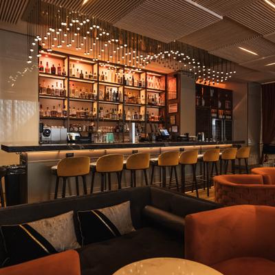 Elegant bar seating with stools and backlit shelves of liquor.