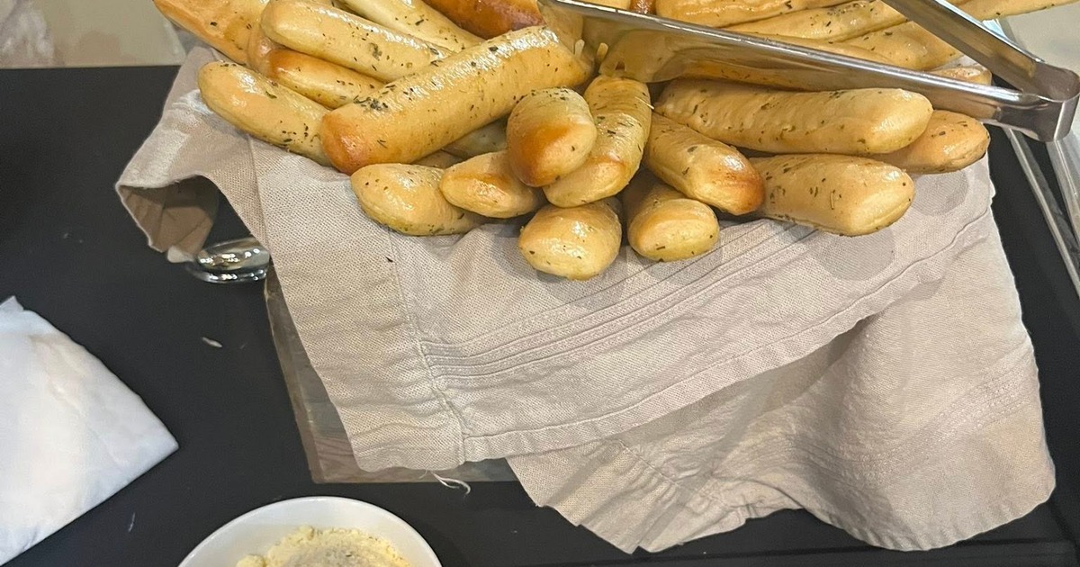 Basket of breadsticks beside a bowl of grated cheese