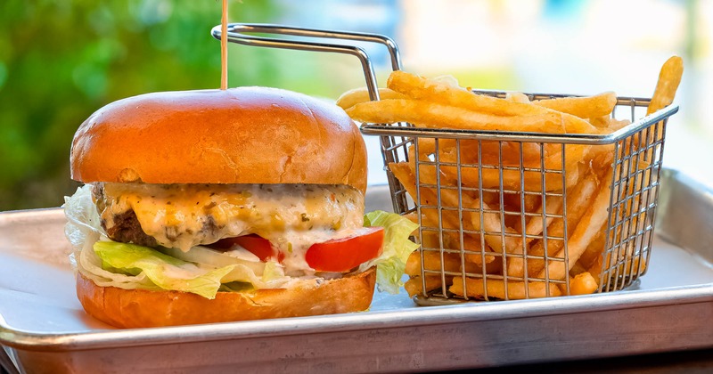 Cheeseburger and a basket of fries served on a tray outside