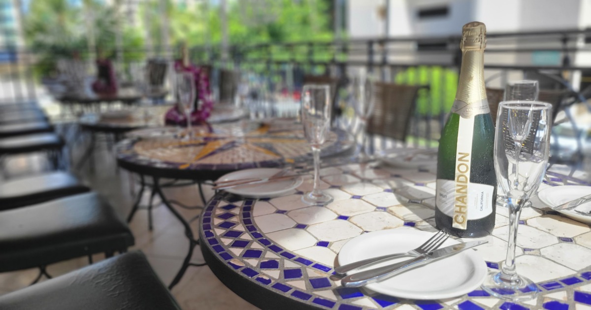 Dining tables with plates, utensils, glasses, and sparkling wine