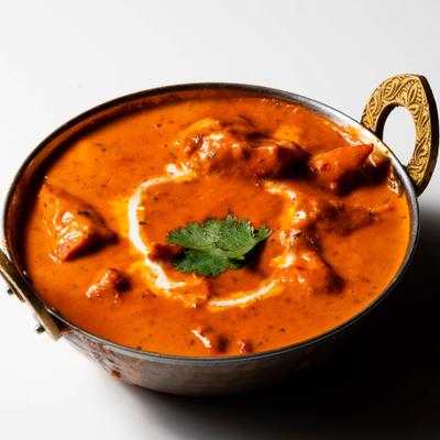 Butter chicken in a metal bowl.