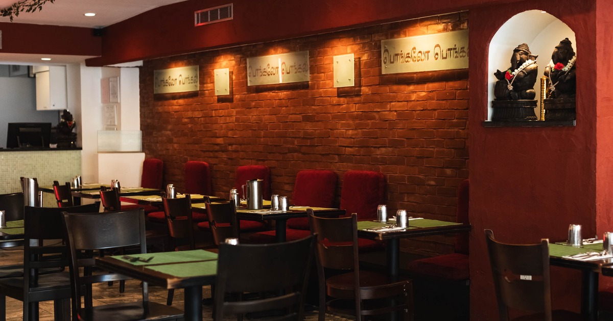 Interior - brick walls, tables set with green placemats and decorated statues in an alcove.