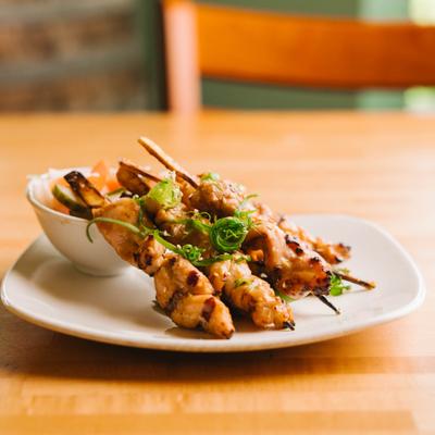 Chicken skewers with sauce on white plate.