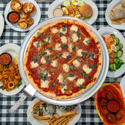 Margherita pizza surrounded by assorted dishes.