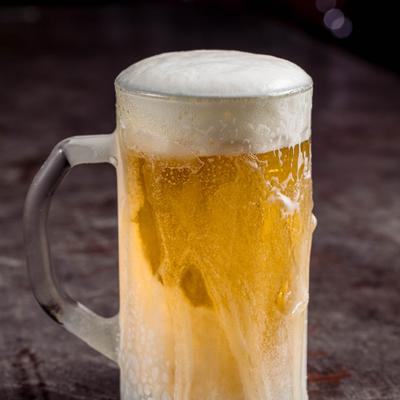 Beer mug filled with light beer and thick foam.
