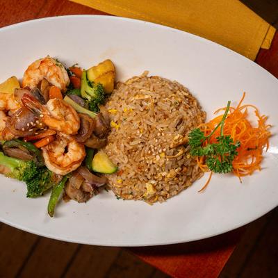Spicy stir fried vegetables, rice, and shrimp served on a white plate.