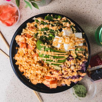 Salmon poke bowl, with rice, sauce, and veggies.