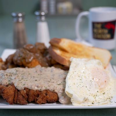 Chicken fried steak with gravy and eggs.