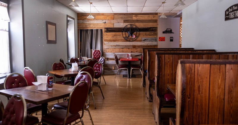 Interior of a rustic dining room with wooden booths and red upholstered chairs