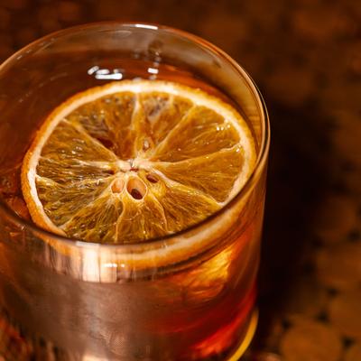 Cocktail with an orange wheel in a short glass.