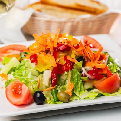 Salad with lettuce, tomato, cucumber, onion, olives, sweet red peppers, and carrots.