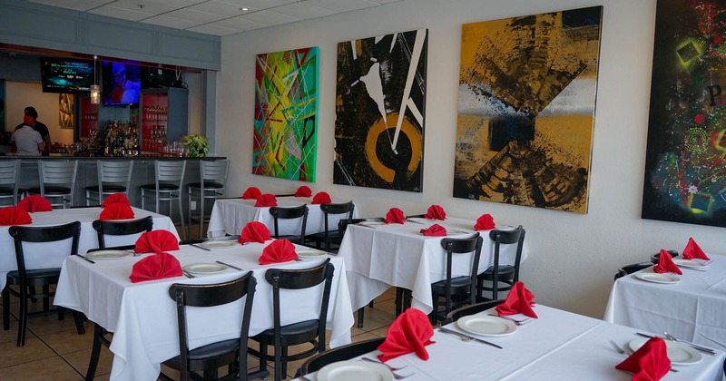 Interior, tables and chairs, painting decorated wall, bar and bar stools in the back