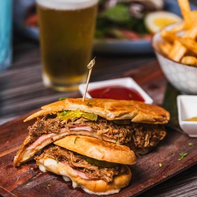Cuban sandwich served with fries and a glass of beer.