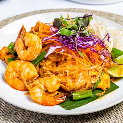 Shrimp Pad Thai with scallions, purple cabbage, and microgreen garnish.