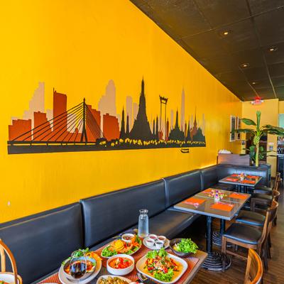 Dining area with table filled with various dishes and a skyline mural on the wall.