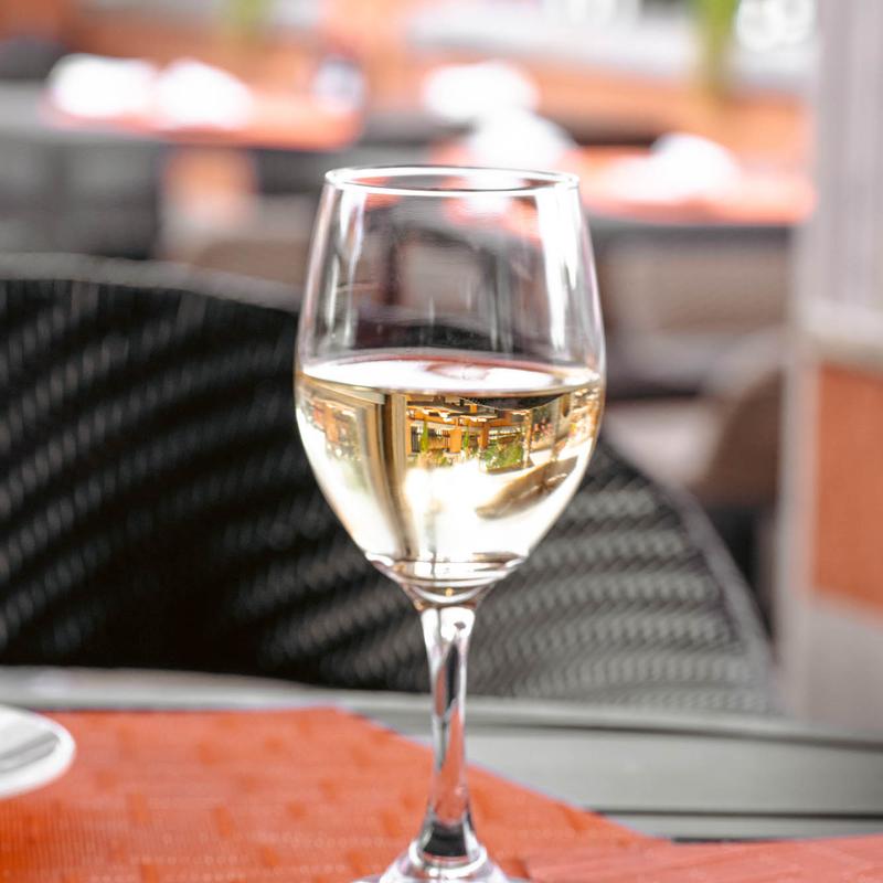 White wine glass on a patio table, blurred background