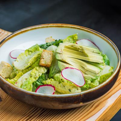 Salad with lettuce, avocado, croutons, and dressing.