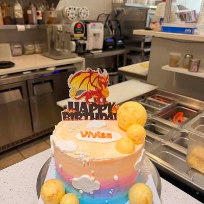 Pastel birthday cake decorated with  white clouds, pearls, and yellow sphere details.