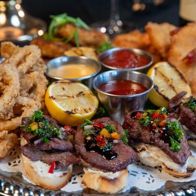 Tasting Platter with calamari, crab cakes, fried shrimp, beef, grilled lemon, and dips.