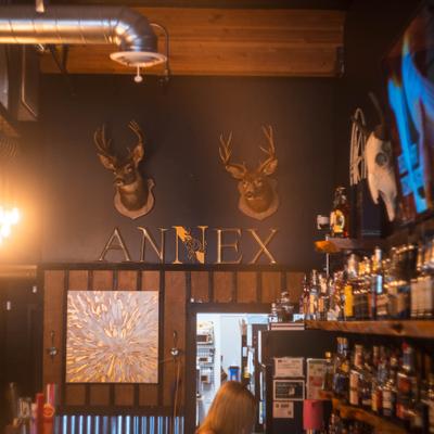 Dark wall bar interior with Annex sign, deer heads and wooden paneling.