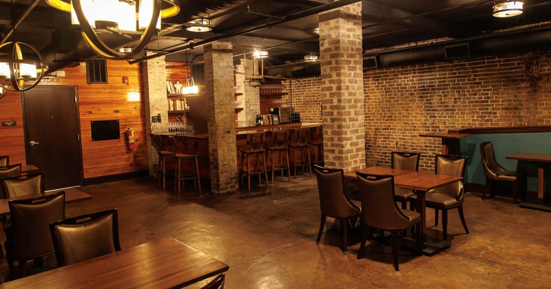 Rustic bar & dining area - exposed brick, wood paneling, leather chairs, tables & a back bar.