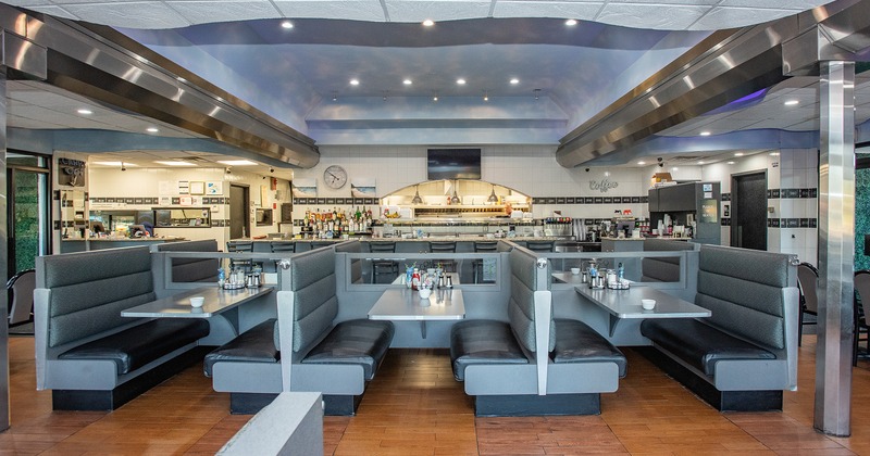 Cozy interior dining area with upholstered dining booths and open kitchen behind