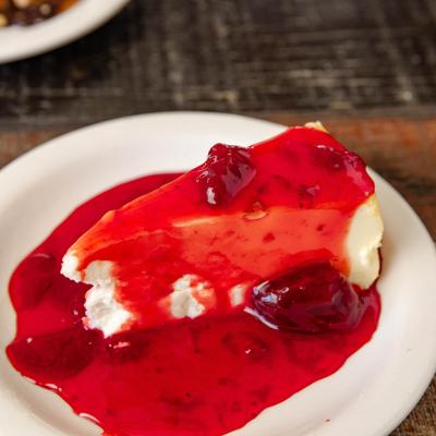 Slice of Cheesecake topped with strawberry sauce.