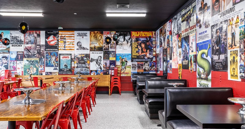 Chairs and tables, black leather booths on the right, movie posters on the walls