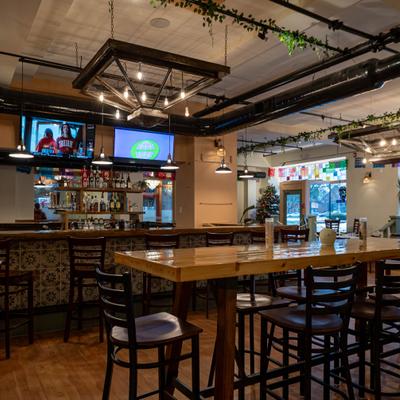 Interior with a wooden bar, high-top tables and industrial-style lighting.