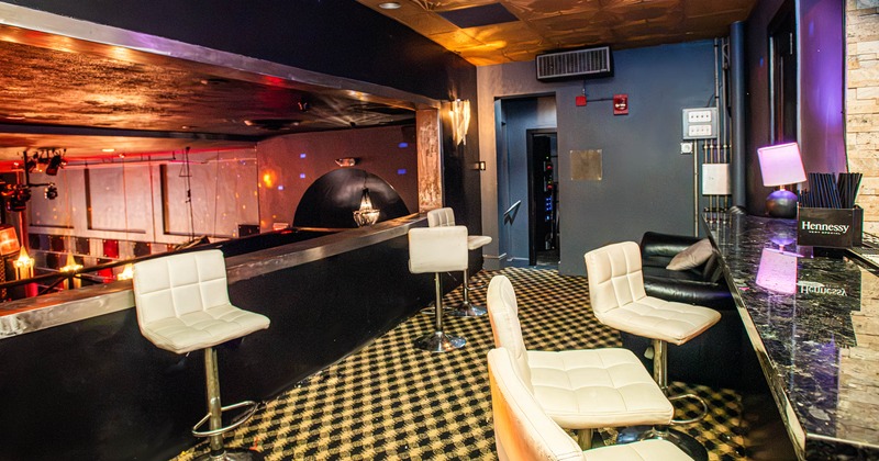 Interior featuring a polished  bar counter, white tufted bar stools, and a patterned carpet