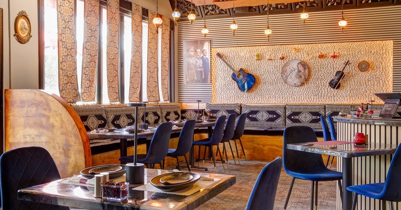 Modern interior dining area with traditional design elements, blue velvet chairs and set tables