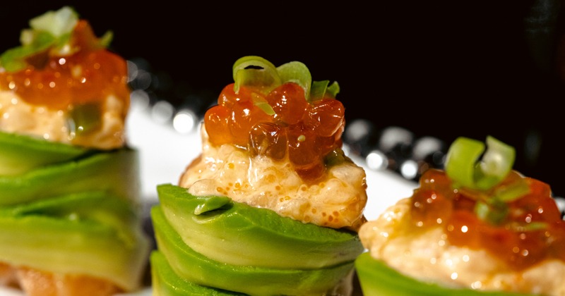 Three canapes with avocado, cream, and salmon roe