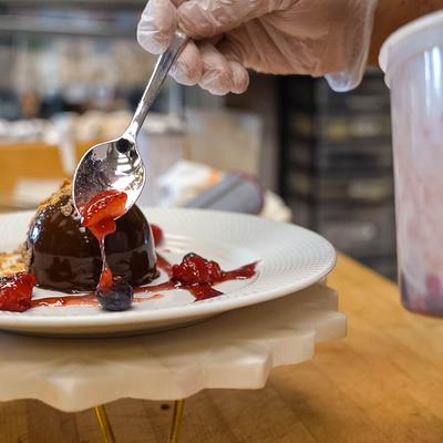 Kitchen staff adding strawberry sauce garnish to Peanut Butter Bomb dessert