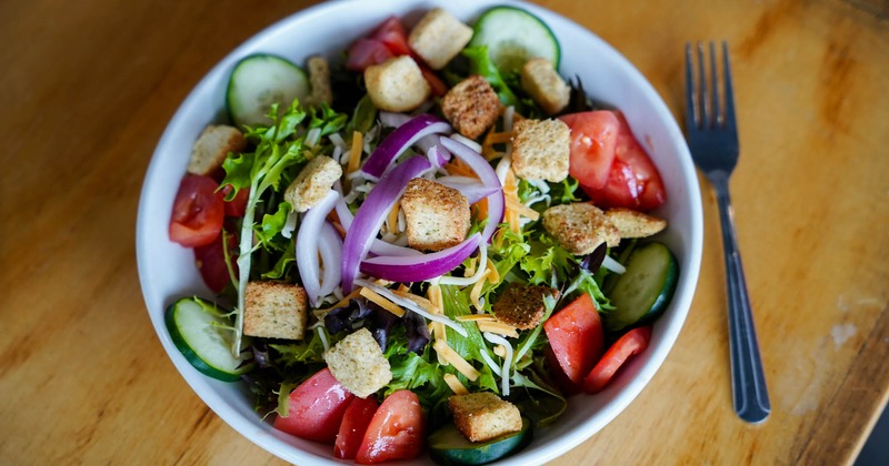 A salad with greens, vegetables and croutons