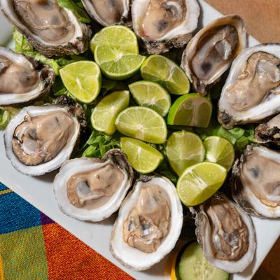 Fresh oysters served on a bed of greens with lime wedges.