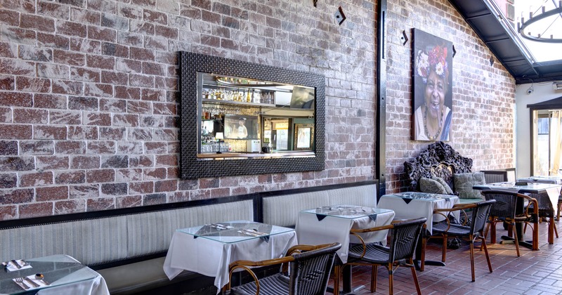 Indoor dining area with brick walls, a mirror, tables with white tablecloths