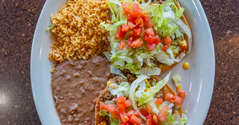 Ground beef tacos, with lettuce, tomato, refried beans, and rice