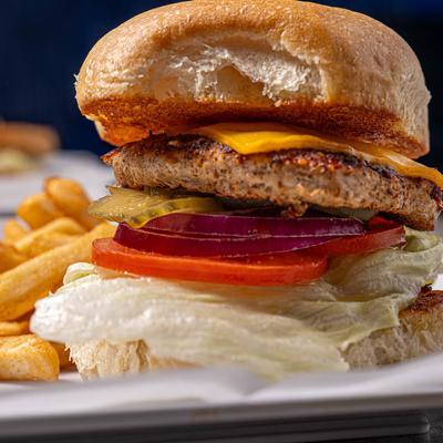Cheeseburger with lettuce, onions, tomatoes, and pickles, served with fries.
