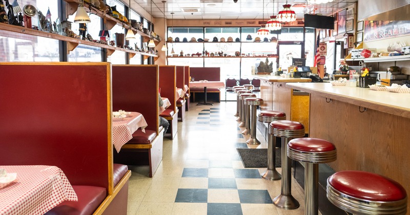 Interior with red booth seating, checkered tablecloths, and a long counter with stools