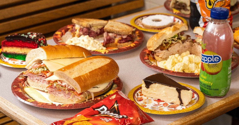 Assorted sandwiches, cake slices, and beverages served on the table