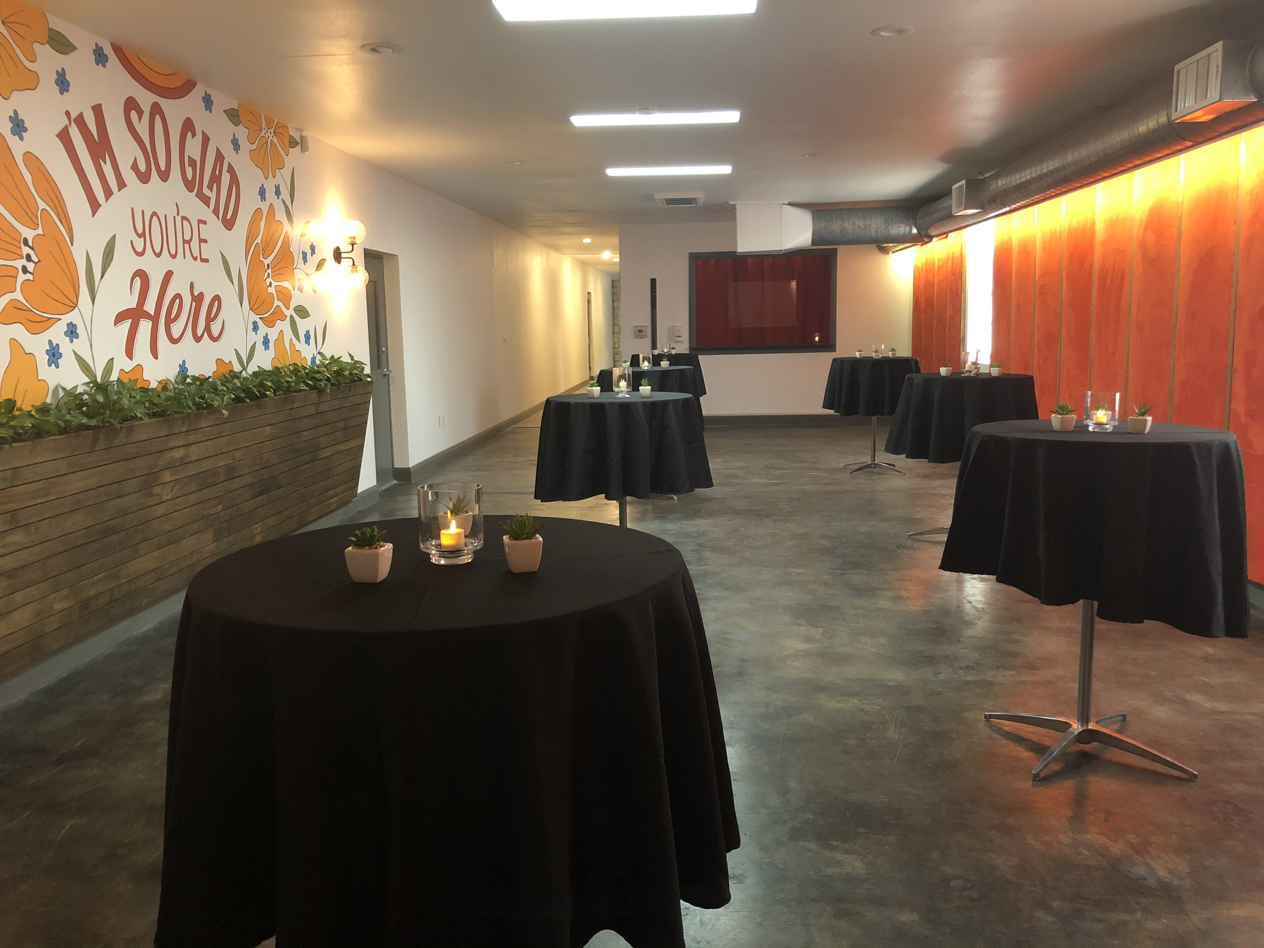 Modern event space with tall tables, black tablecloths, and lit candles